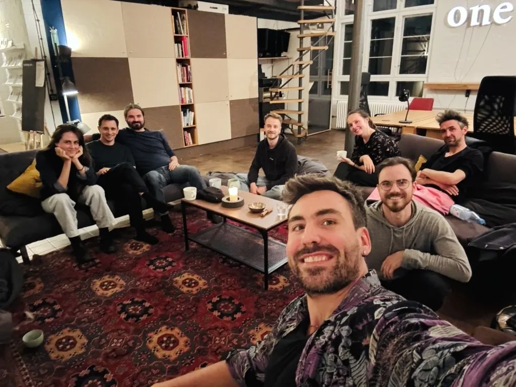 Robin Hotz takes a selfie with eight participants of the Sense-Making Evening, sitting on sofas around a candlelit table at the Cocreation Loft